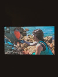 a woman is laying on the rocks next to the ocean