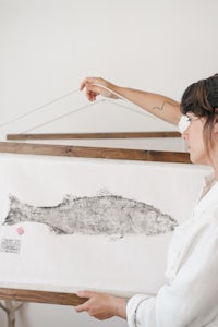 a woman is holding up a print of a fish